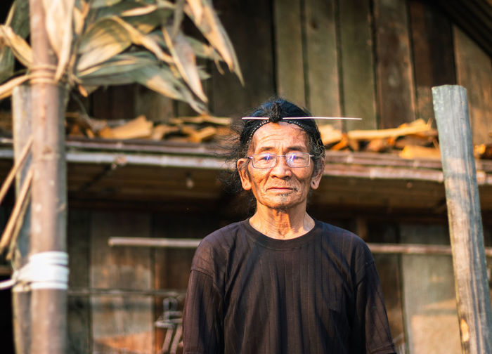 Senior man standing against hut