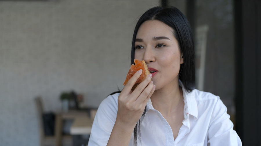 Woman eating food while looking away