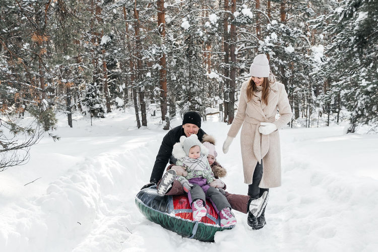 Cheerful family on a weekend rides a sleigh in a snowy forest