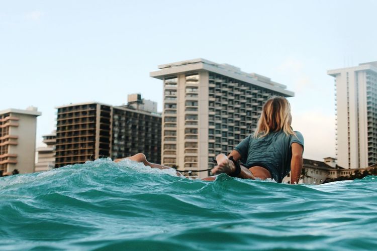 Low angle view of woman swimming in sea against buildings