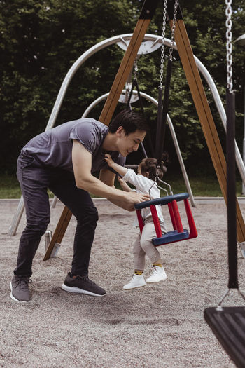 Father carrying son out of swing in playground
