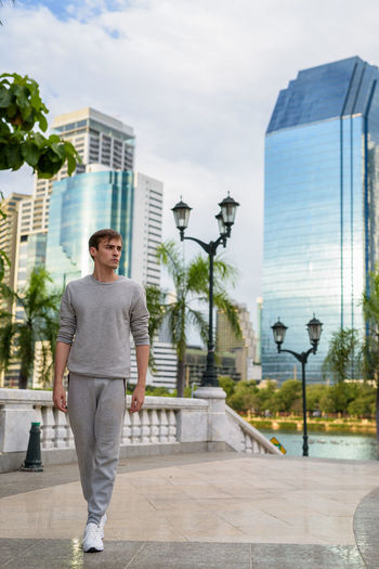 Portrait of young man standing against modern buildings in city