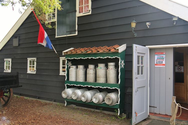 Various milk cans in front of built structure
