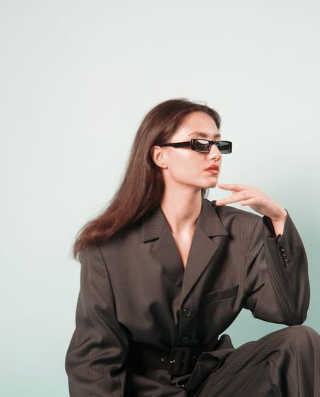 Portrait of young woman wearing sunglasses against white background