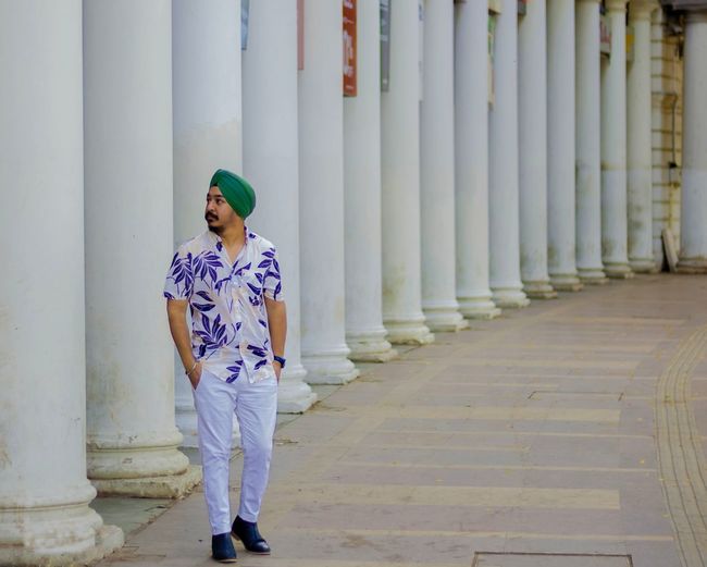 Full length of man wearing turban while standing by colonnade on street