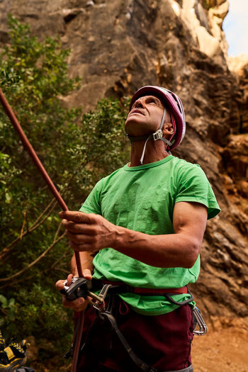 Active senior man holding climbing rope preparing to climb mountain