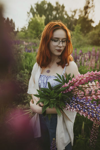 Redhead teenage girl standing with lupin flowers