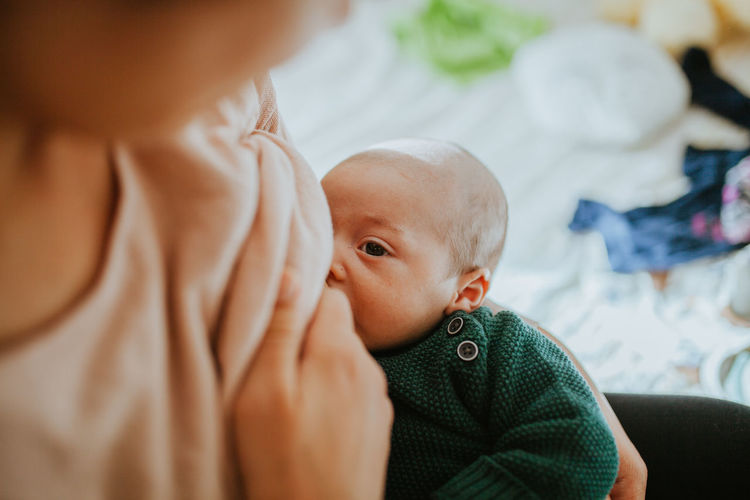 Close-up of mother breastfeeding baby boy while sitting at home