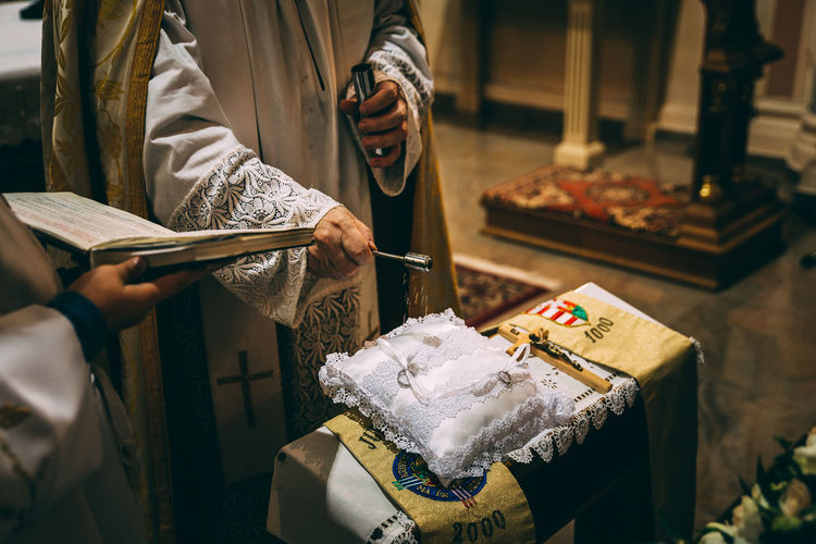 Priest sprinkling holy water on wedding rings at church