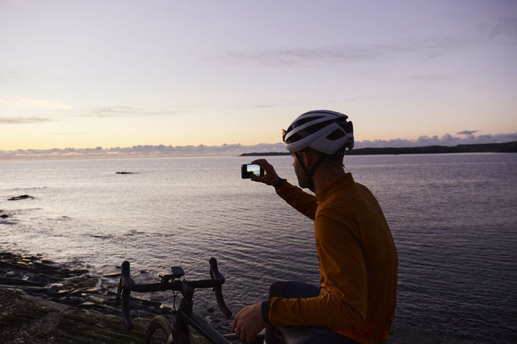 Young cyclist photographing through smart phone