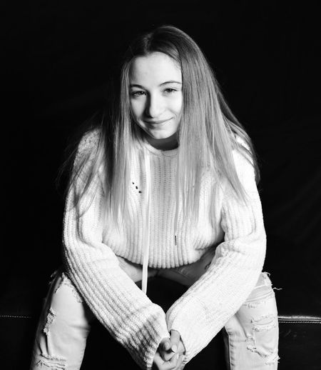 Smiling girl sitting against black background