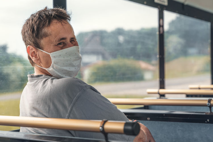  happy woman with an mental disability wears a ffp2 medical mask while she travels by bus or train