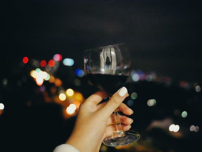 Close-up of hand holding wine glass at night