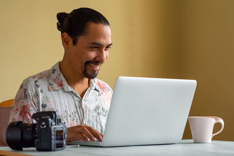 Mid adult man using mobile phone while sitting on table