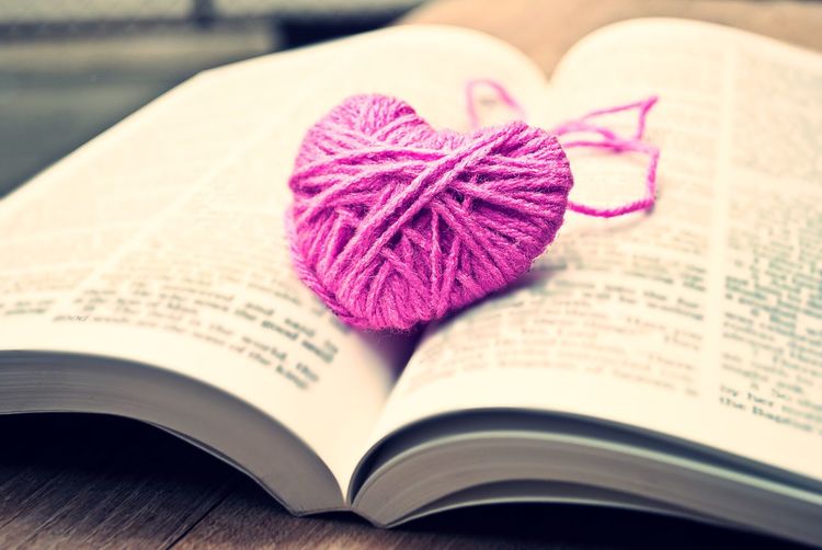 Close-up of knitted pink heart on open book