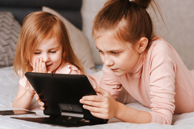 Young woman using laptop while sitting on bed at home