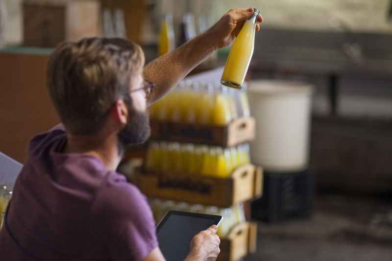 Man checking stock of juice bottles in warehouse