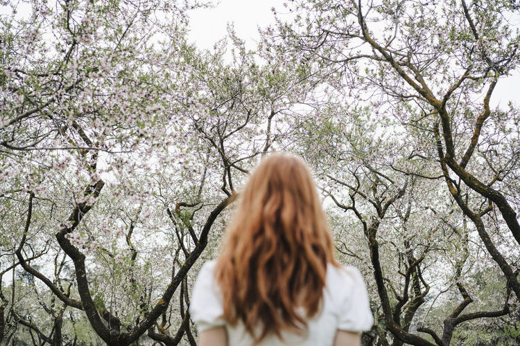 Redhead woman in front of almond tree