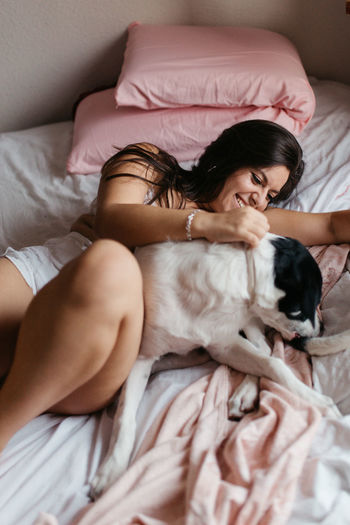 Midsection of woman with dog on bed at home