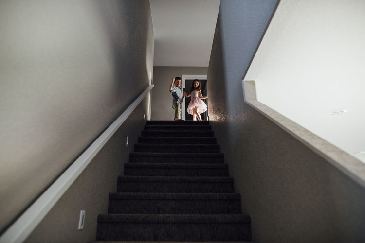 Low angle view of siblings standing on steps at home