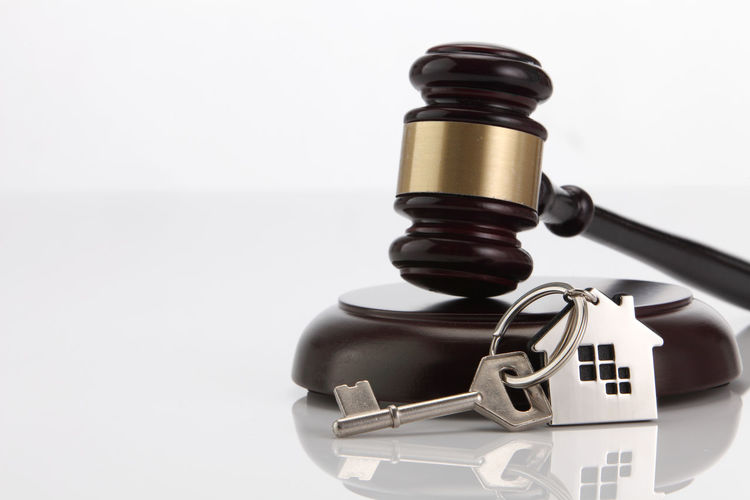 Close-up of gavel with key against white background