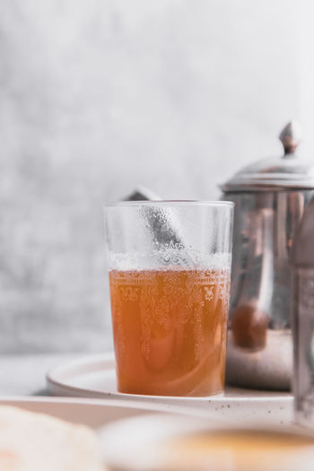 Close-up of moroccan mint tea being poured in glass on grey table