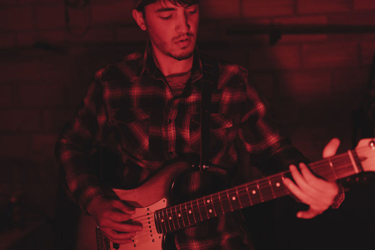 Group of musicians playing in red neon lights at music studio