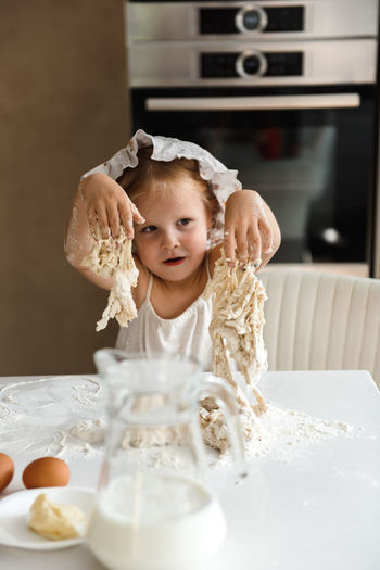 Little girl cooking pizza in the kitchen