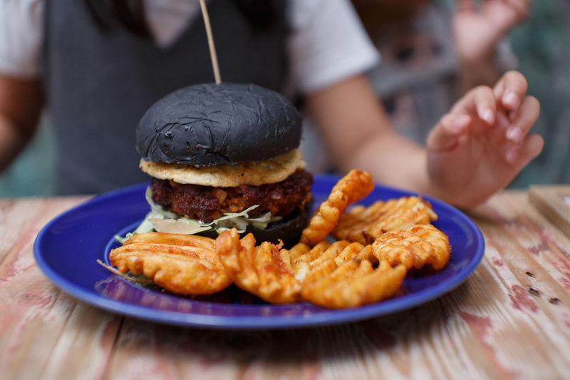 Close-up of charcoal bread burger served in plate on table
