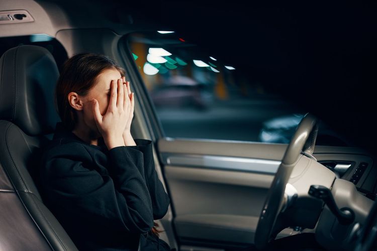 Woman covering face while sitting in car