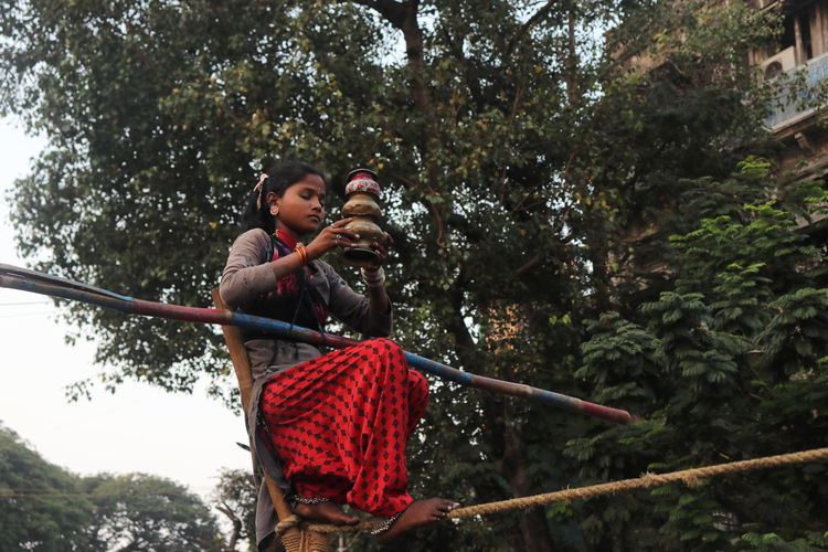 A young street performer prepares to balance pots on her head before commencing tight rope walking