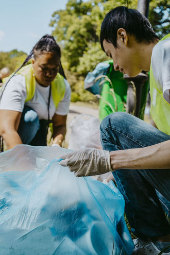 Male environmentalist picking up plastics with female volunteer