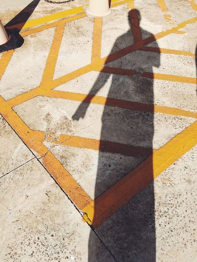 Shadow of person on footpath during sunny day