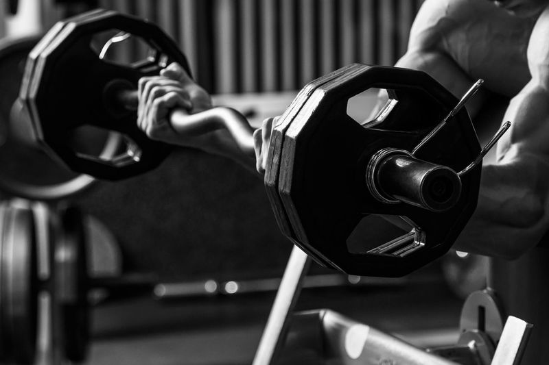 Cropped hand of man lifting dumbbell in gym