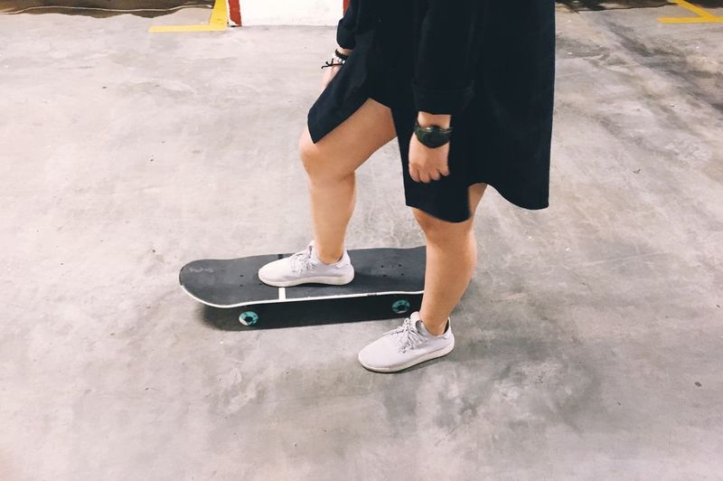 Low section of woman with skateboard on road
