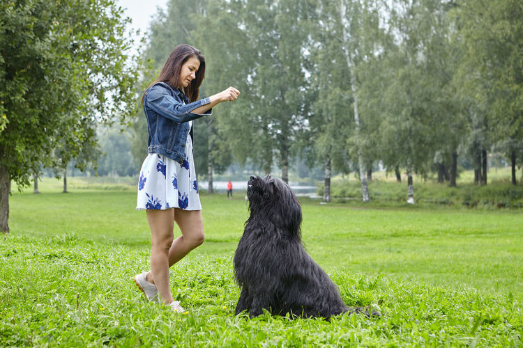 Full length of woman with dog standing on grass