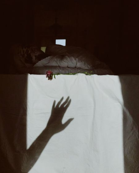 Shadow of person hand on bed at home
