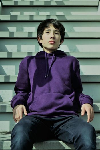 Teenage boy sitting against on staircase