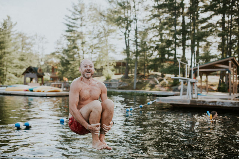 Full length portrait of shirtless man jumping in lake