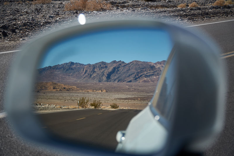 Reflection of mountains on side-view mirror of car