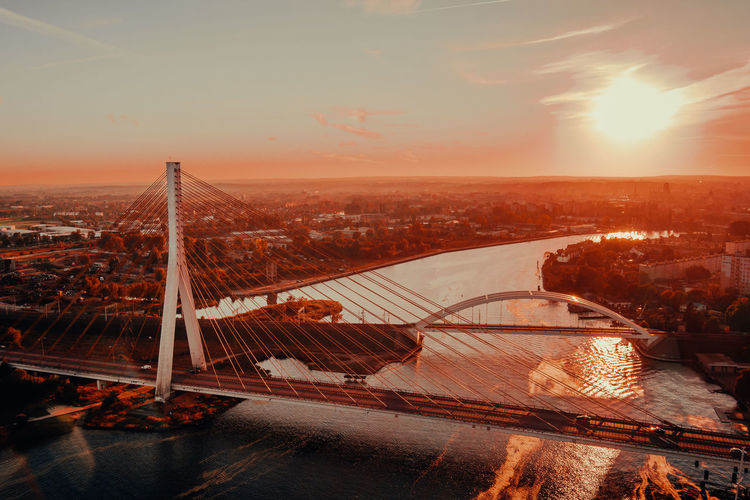 Bridge over river in city during sunset