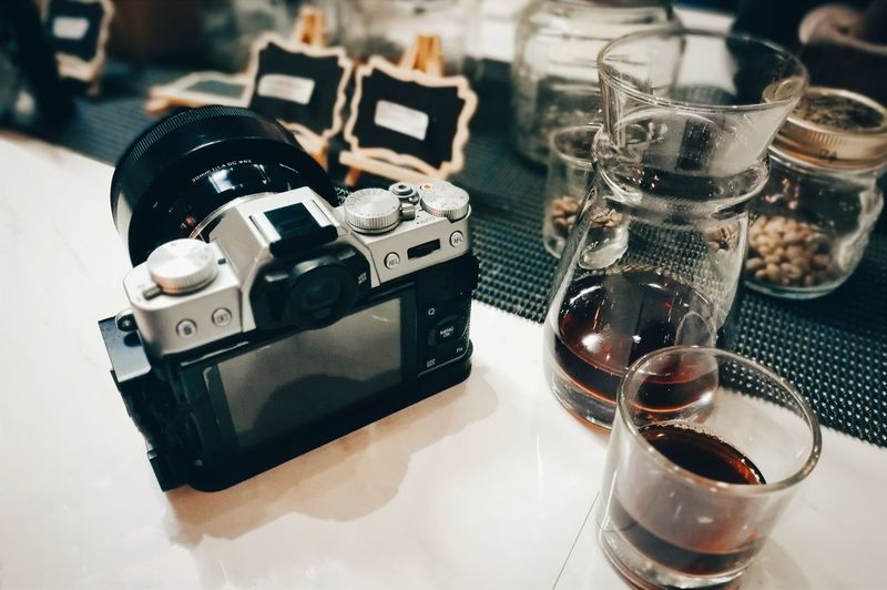 Close-up of camera and black coffe on table