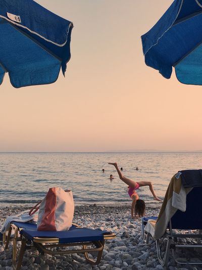 Low section of people standing on beach against clear sky