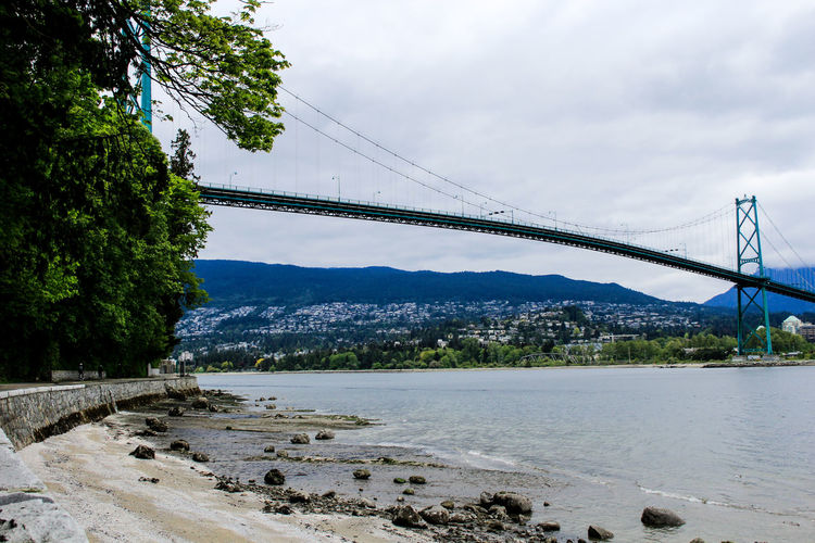 Bridge over river against cloudy sky