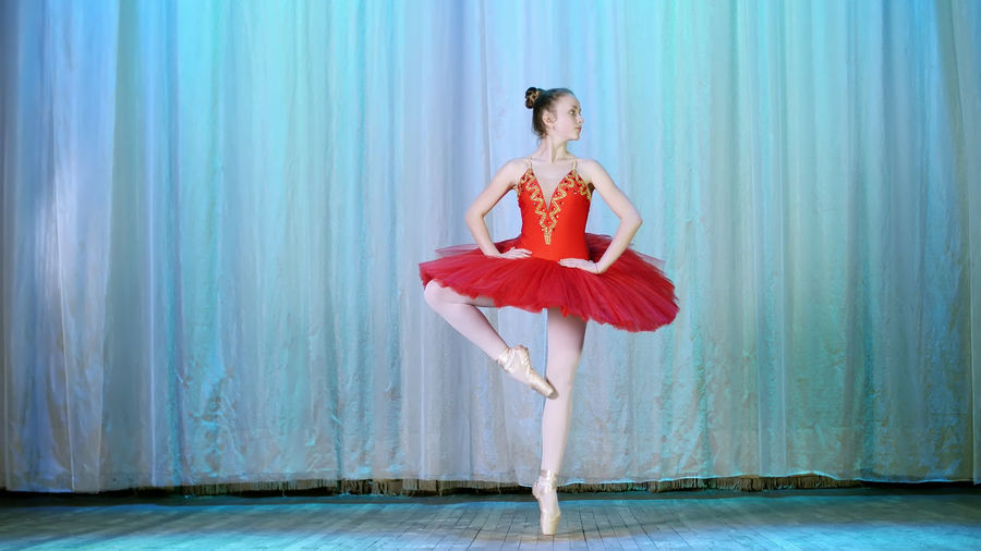 Ballet rehearsal, on the stage of the old theater hall. young ballerina in red ballet tutu 