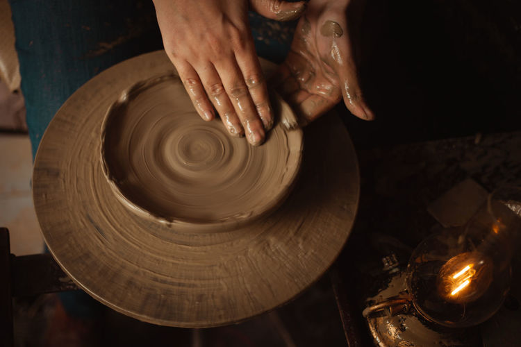 Woman makes plate of clay in pottery workshop, beautiful background, authentic atmosphere