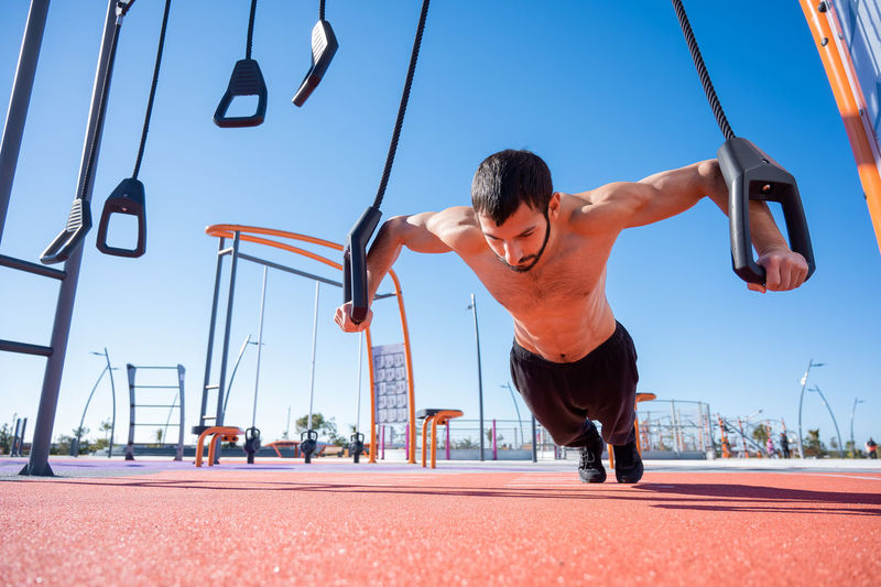 Low angle view of shirtless athlete exercising in playground