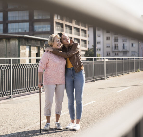 Granddaughter and her grandmother standing on footbridge