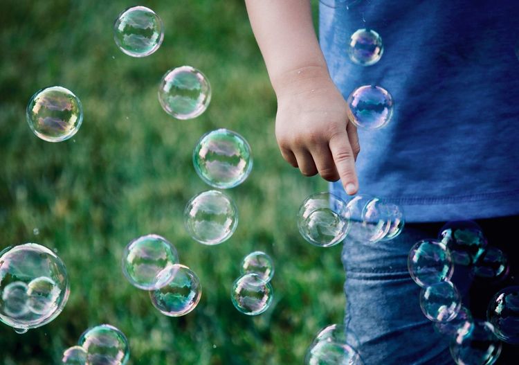 Midsection of boy playing with bubbles at park