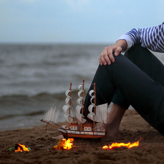 Low section of woman sitting on beach against sky